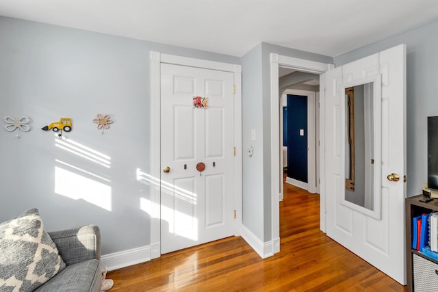 interior space featuring arched walkways, baseboards, and wood finished floors