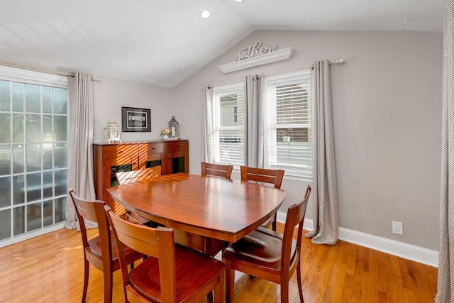 dining room with baseboards, light wood-style floors, and lofted ceiling