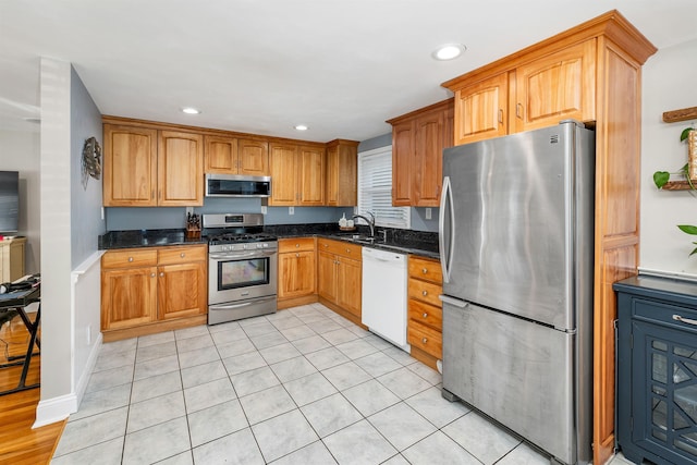 kitchen with dark stone countertops, recessed lighting, appliances with stainless steel finishes, and a sink