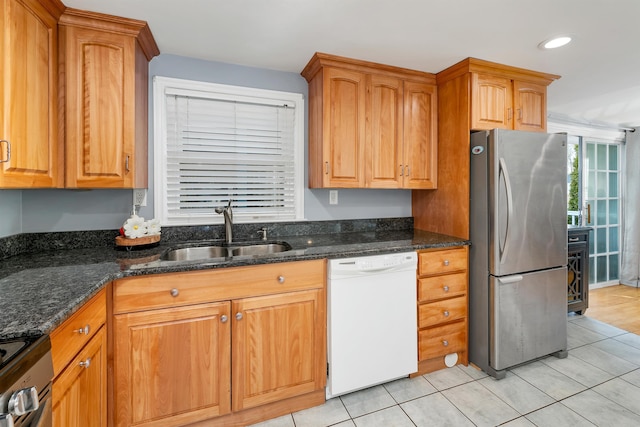 kitchen with dark stone counters, light tile patterned floors, recessed lighting, appliances with stainless steel finishes, and a sink