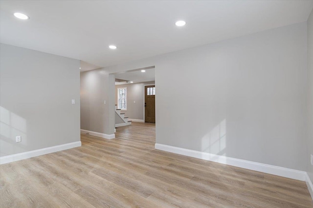 empty room with recessed lighting, light wood-type flooring, baseboards, and stairway