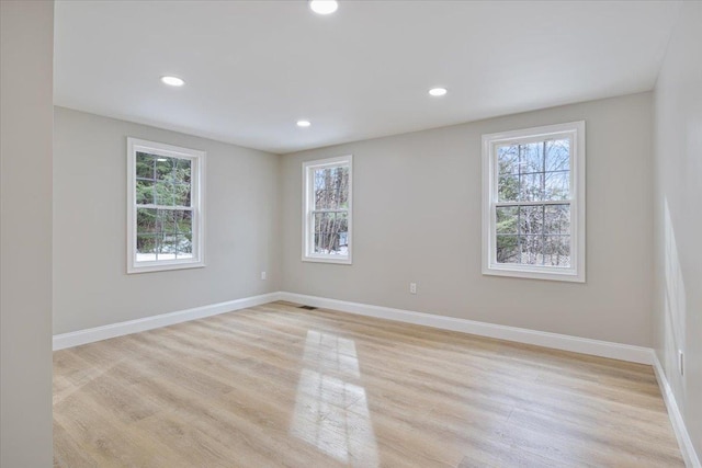 empty room featuring a wealth of natural light, baseboards, recessed lighting, and light wood finished floors