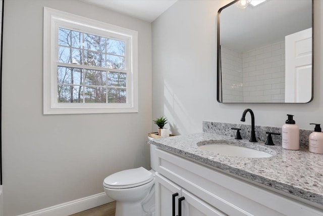 bathroom with toilet, vanity, and baseboards