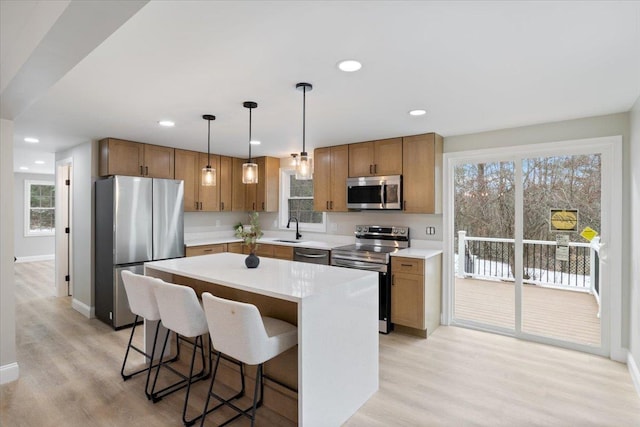 kitchen featuring stainless steel appliances, light wood-style floors, a kitchen breakfast bar, decorative light fixtures, and a center island