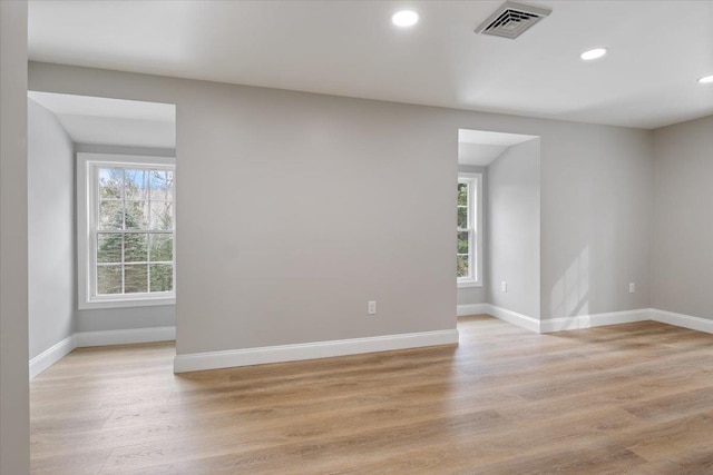 empty room featuring visible vents, plenty of natural light, baseboards, and light wood-style floors