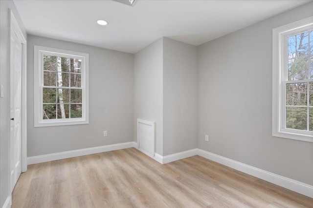 empty room featuring recessed lighting, baseboards, and light wood finished floors