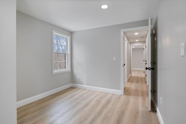 empty room featuring recessed lighting, baseboards, and light wood finished floors