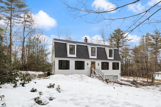 dutch colonial with central AC unit, a gambrel roof, a chimney, a shingled roof, and a garage