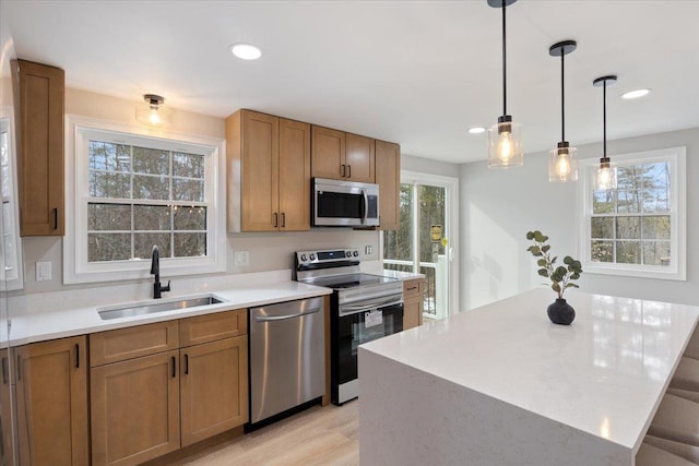 kitchen featuring brown cabinets, stainless steel appliances, light countertops, and a sink