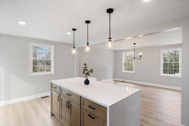 kitchen featuring light wood-style floors, baseboards, a wealth of natural light, and a kitchen island