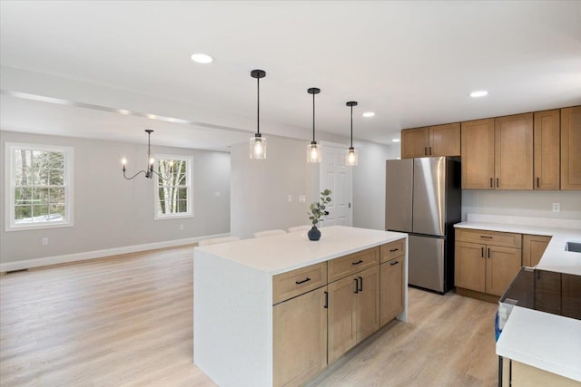 kitchen with a wealth of natural light, light wood-type flooring, freestanding refrigerator, and a kitchen island