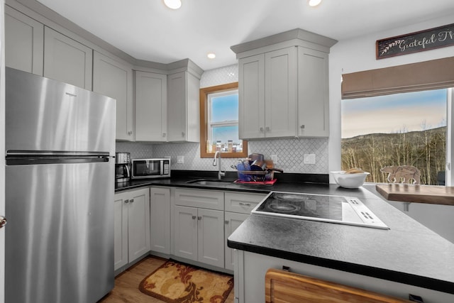 kitchen with recessed lighting, a sink, stainless steel appliances, dark countertops, and backsplash