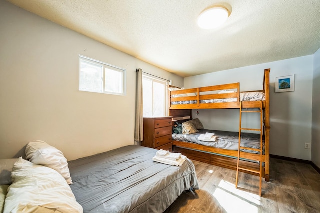 bedroom with wood finished floors, baseboards, and a textured ceiling