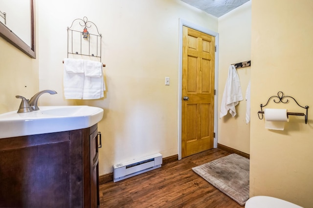 bathroom featuring baseboards, toilet, wood finished floors, vanity, and a baseboard radiator