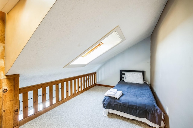 bedroom with vaulted ceiling with skylight, baseboards, and carpet