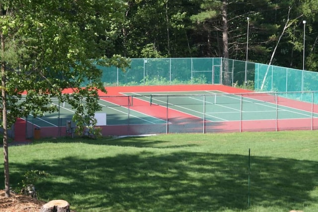 view of tennis court featuring a yard and fence