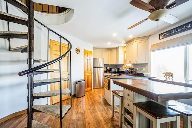 kitchen with recessed lighting, stainless steel appliances, decorative backsplash, dark countertops, and light wood-type flooring