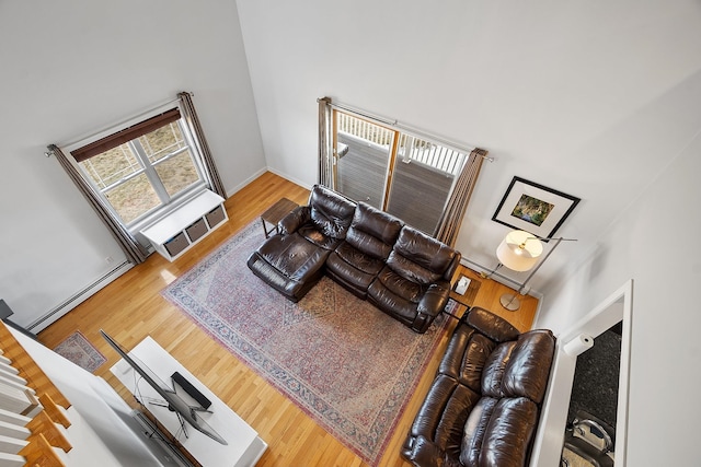 living room with a high ceiling, wood finished floors, baseboards, and baseboard heating