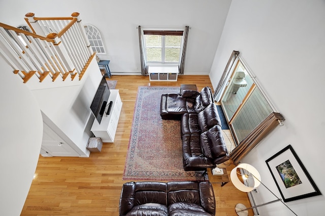 living area with stairs, light wood-style flooring, and a baseboard heating unit