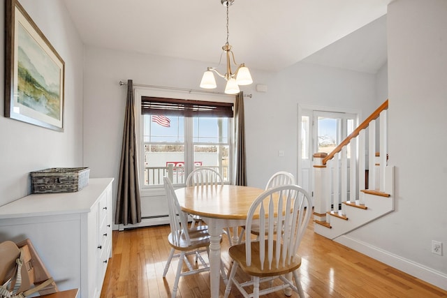 dining space with light wood finished floors, baseboards, a chandelier, stairway, and baseboard heating