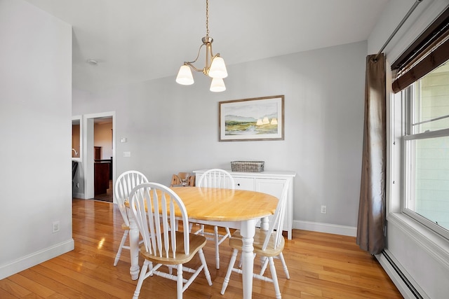 dining space featuring light wood finished floors, a notable chandelier, baseboards, and a baseboard radiator