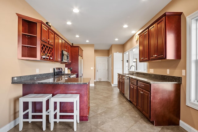 kitchen featuring a breakfast bar area, recessed lighting, appliances with stainless steel finishes, a peninsula, and open shelves