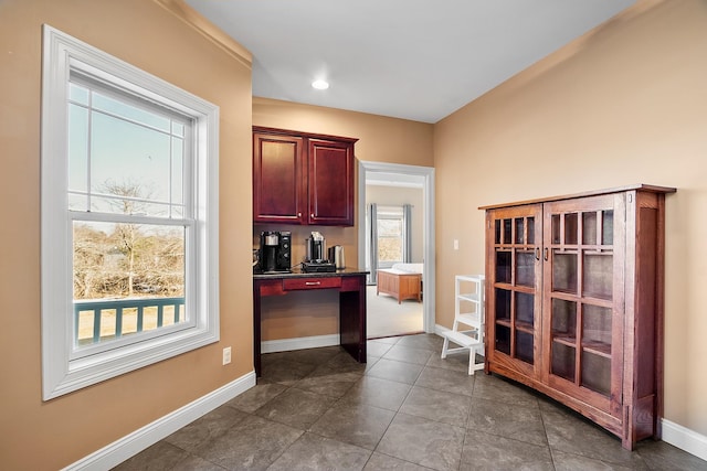 kitchen with dark countertops, plenty of natural light, baseboards, and dark brown cabinets