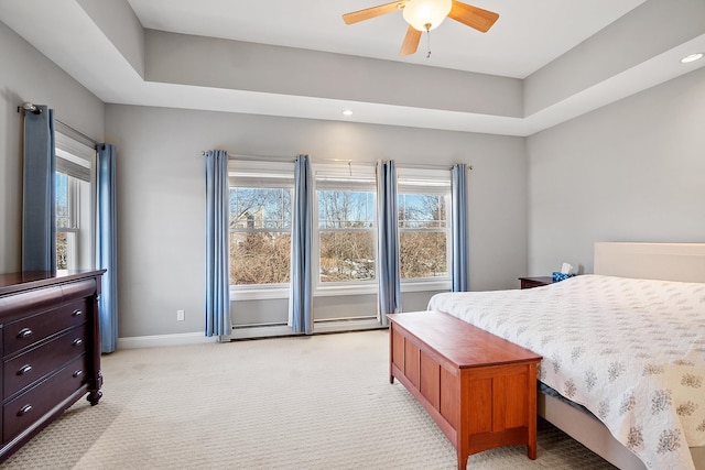 bedroom featuring a ceiling fan, baseboards, light carpet, a raised ceiling, and baseboard heating