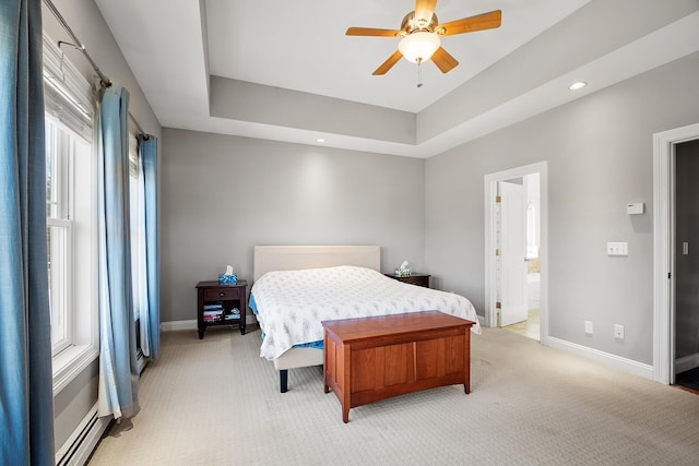 bedroom with a baseboard radiator, a raised ceiling, baseboards, and light carpet