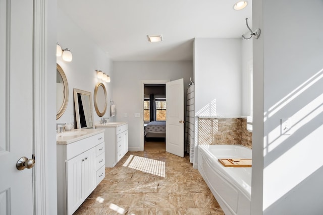 bathroom featuring a garden tub, two vanities, ensuite bathroom, and a sink