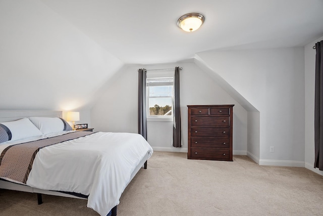 bedroom featuring lofted ceiling, baseboards, and light carpet