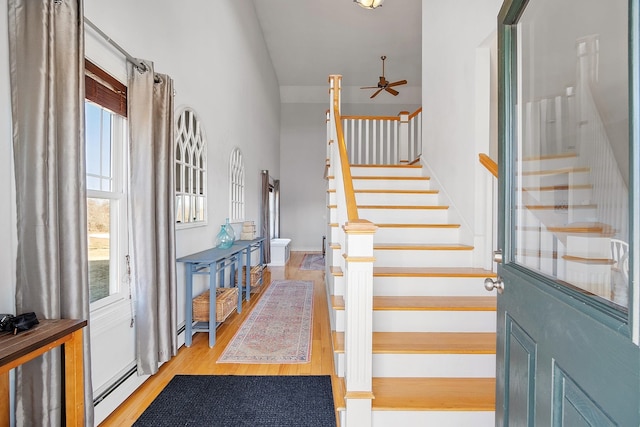 foyer with stairs, wood finished floors, a healthy amount of sunlight, and a baseboard radiator