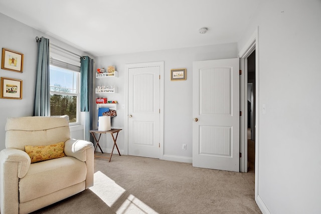 sitting room featuring light carpet and baseboards