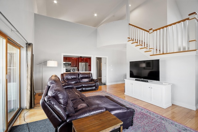 living room featuring light wood-style floors, baseboards, and high vaulted ceiling