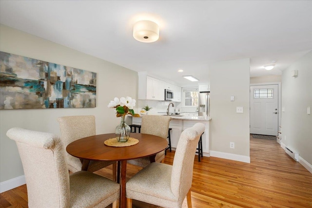 dining space featuring a baseboard heating unit, recessed lighting, light wood-style floors, and baseboards