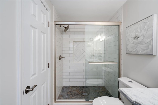 bathroom featuring vanity, a shower stall, and toilet