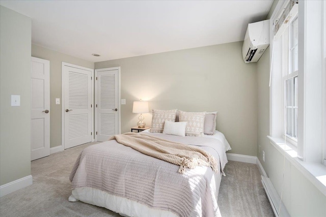 bedroom with light colored carpet, baseboards, and a wall mounted AC