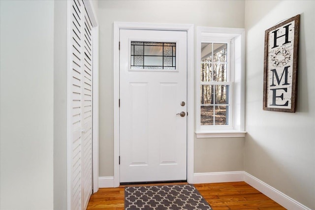 doorway featuring baseboards and light wood finished floors