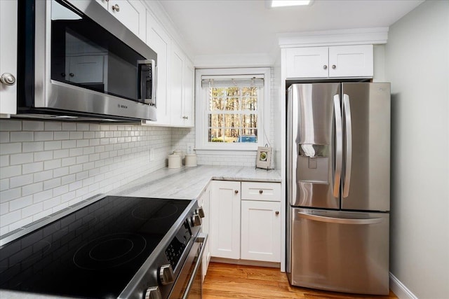 kitchen featuring decorative backsplash, light stone counters, white cabinetry, and appliances with stainless steel finishes