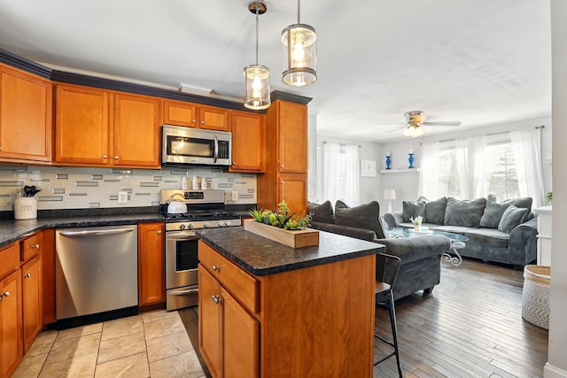 kitchen with brown cabinets, a breakfast bar, tasteful backsplash, a kitchen island, and stainless steel appliances