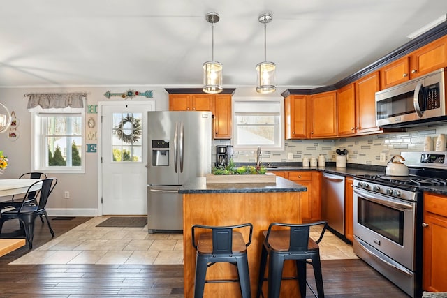 kitchen with tasteful backsplash, appliances with stainless steel finishes, a center island, and dark countertops