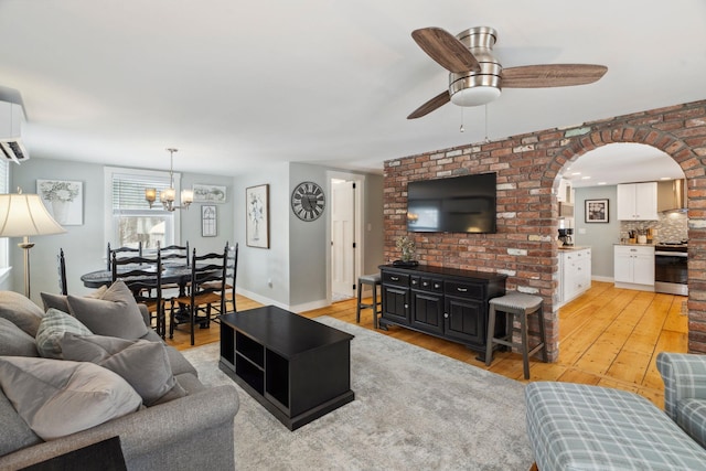 living area with ceiling fan, baseboards, arched walkways, and light wood-style flooring