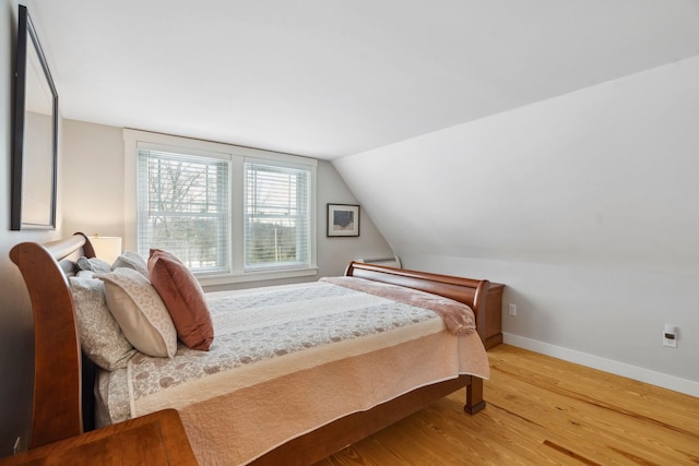 bedroom featuring baseboards, wood finished floors, and vaulted ceiling