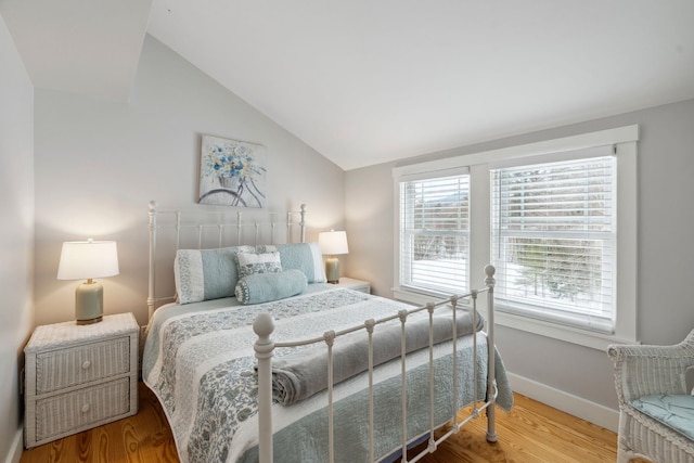 bedroom with baseboards, wood finished floors, and vaulted ceiling