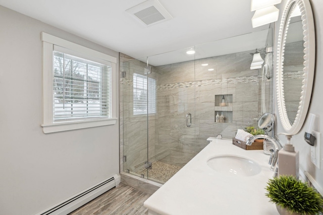 bathroom with vanity, wood finished floors, visible vents, a baseboard radiator, and a shower stall