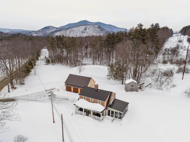 snowy aerial view with a mountain view and a wooded view