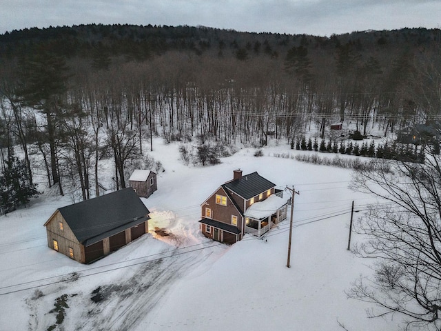 snowy aerial view featuring a forest view