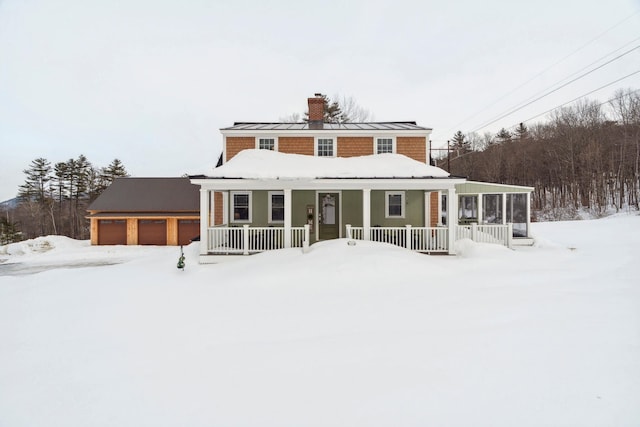 view of front of property with a standing seam roof, covered porch, metal roof, a garage, and a chimney