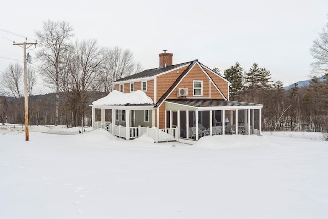 snow covered house featuring a sunroom and a chimney