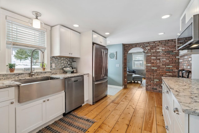 kitchen featuring arched walkways, plenty of natural light, appliances with stainless steel finishes, and a sink